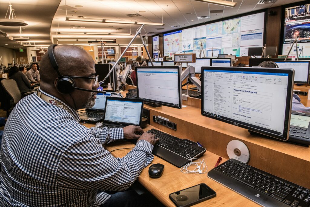 A employees speaking in front of several computer screens.